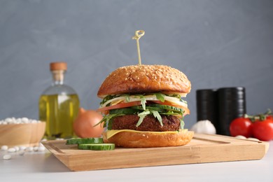 Photo of Board with delicious vegetarian burger on white table