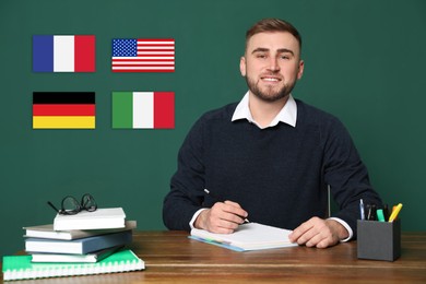 Image of Portrait of foreign languages teacher at wooden table and different flags green chalkboard