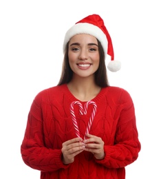 Photo of Young woman in red sweater and Santa hat holding candy canes on white background