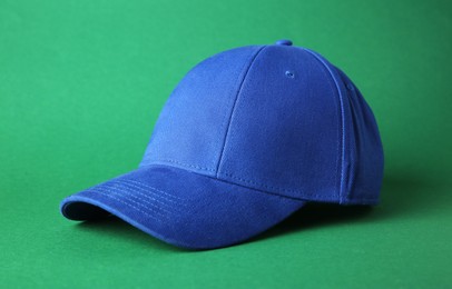 Photo of Stylish blue baseball cap on green background