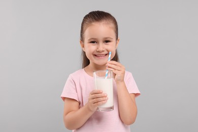 Photo of Cute girl with glass of fresh milk on light grey background