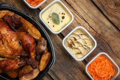 Photo of Plastic containers with different dishes on wooden table, flat lay. Food delivery service