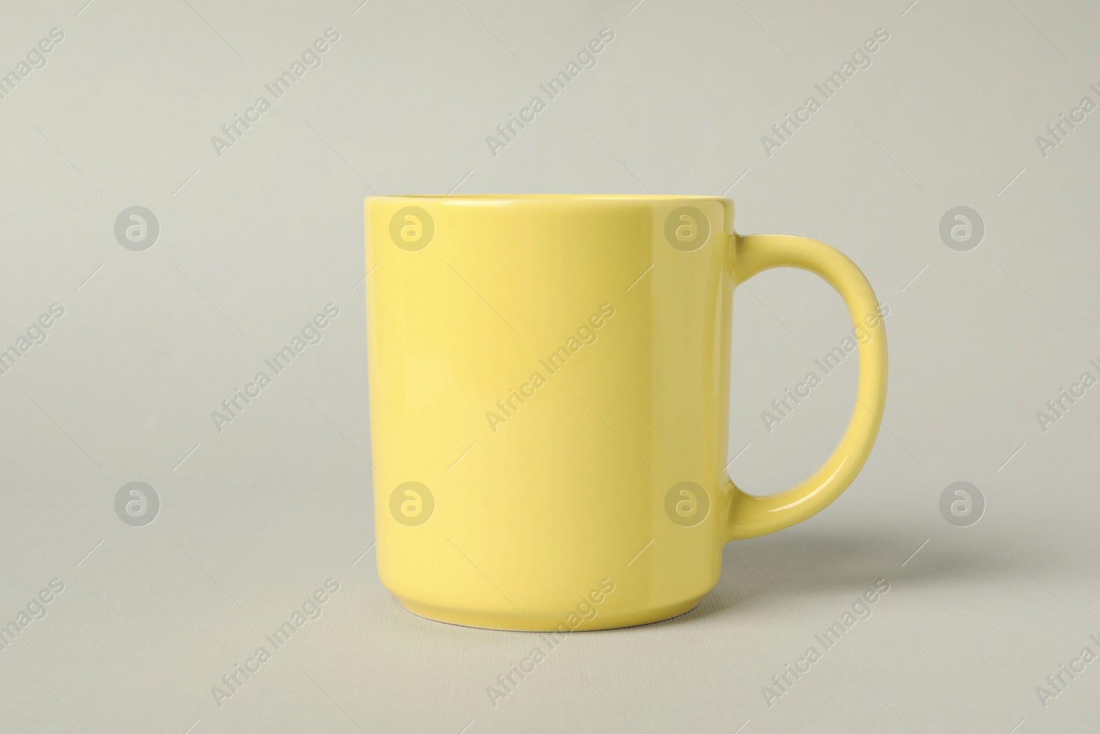 One yellow ceramic mug on light grey background Photo of One yellow ceramic mug on light grey background