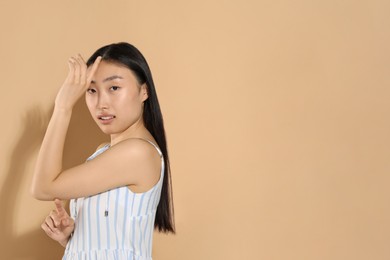 Photo of Beautiful young woman on beige background, space for text