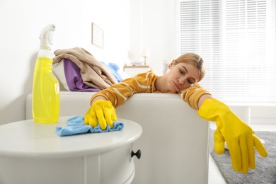 Photo of Lazy young woman wiping table at home. Cleaning and housework