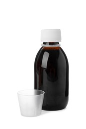 Photo of Bottle of syrup with measuring cup on white background. Cough and cold medicine