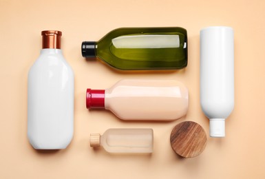 Photo of Bottles of shampoo on beige background, flat lay