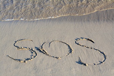 Photo of SOS message written on sand near sea