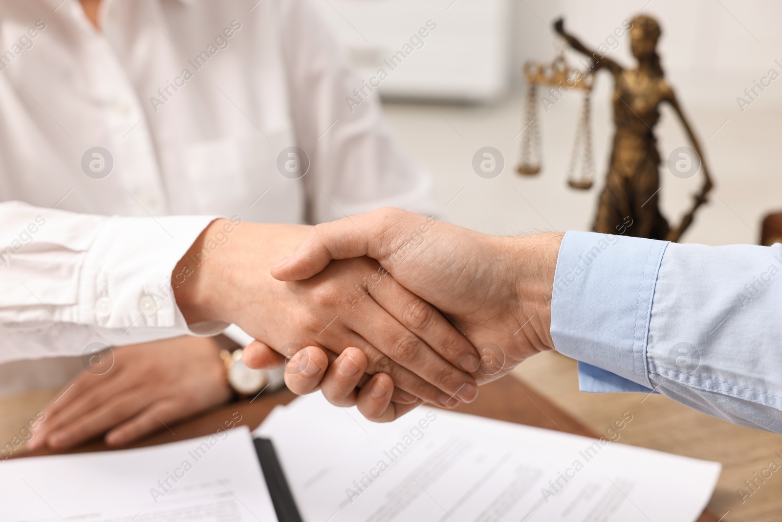 Photo of Lawyers shaking hands at table in office, closeup