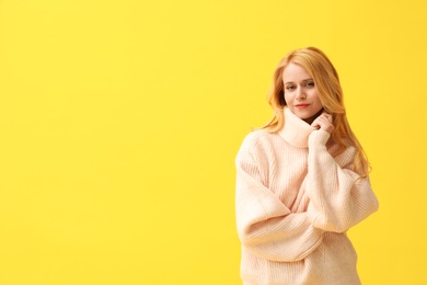 Photo of Beautiful young woman wearing warm pink sweater on yellow background. Space for text