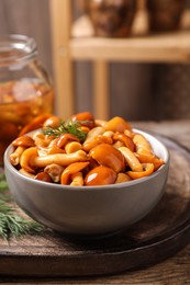 Photo of Tasty marinated mushrooms with dill on wooden table, closeup