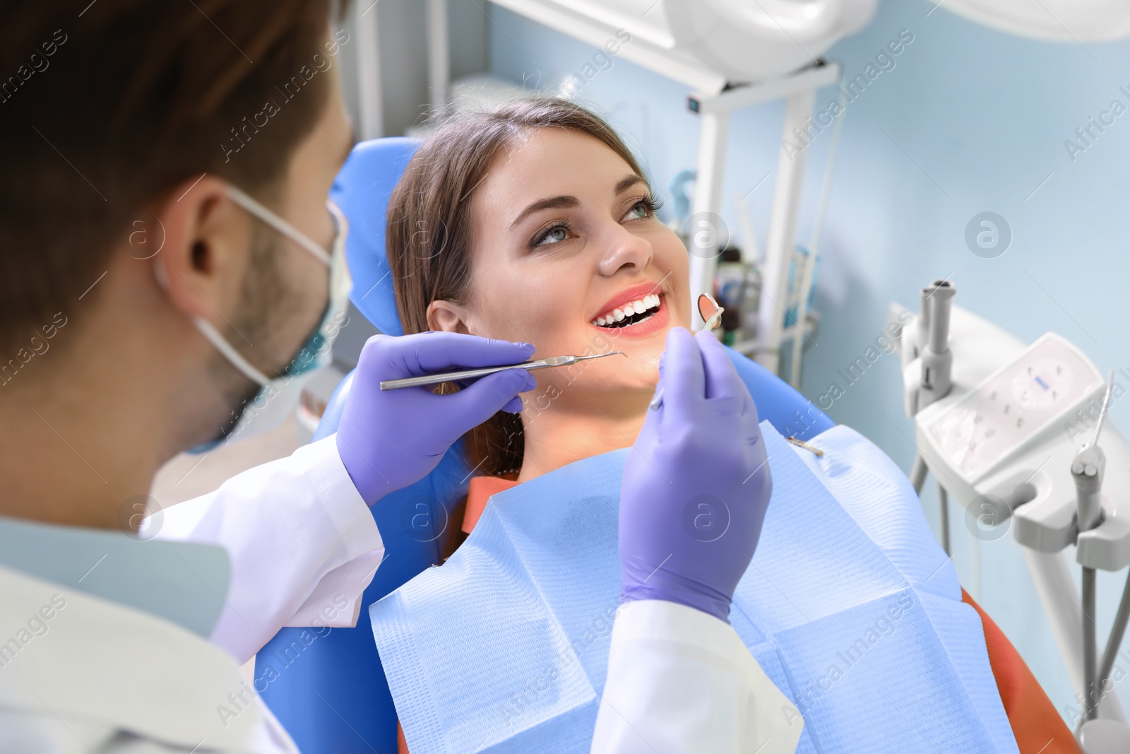 Photo of Professional dentist working with patient in modern clinic