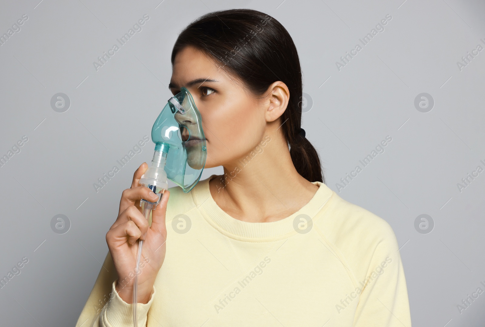 Photo of Sick young woman using nebulizer on grey background