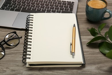 Photo of Notebook, laptop and pen on wooden table