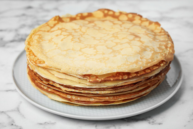 Photo of Stack of fresh thin pancakes on white marble table