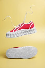 Photo of Pair of red classic old school sneakers on yellow background