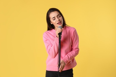 Photo of Young woman wearing casual clothes singing in microphone on color background