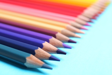 Photo of Colorful pencils on light blue background, closeup