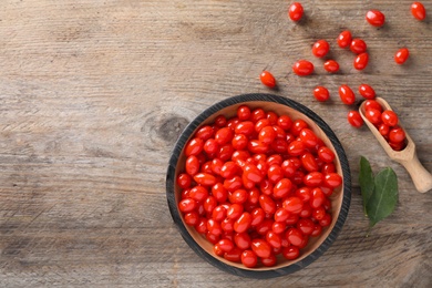 Photo of Fresh ripe goji berries on wooden table, flat lay. Space for text