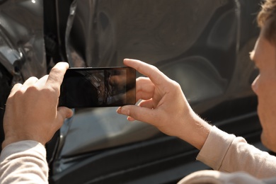 Photo of Man photographing broken car after accident for insurance claim, closeup