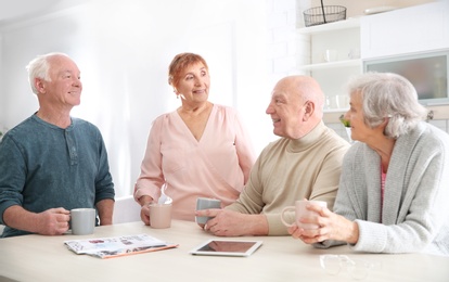 Photo of Elderly people spending time together at table in kitchen