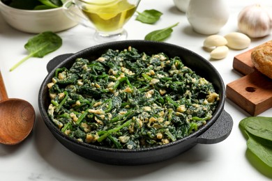 Photo of Tasty spinach dip with eggs in dish served on white table, closeup