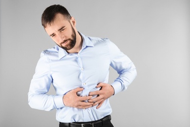 Photo of Young man suffering from abdominal pain on light background
