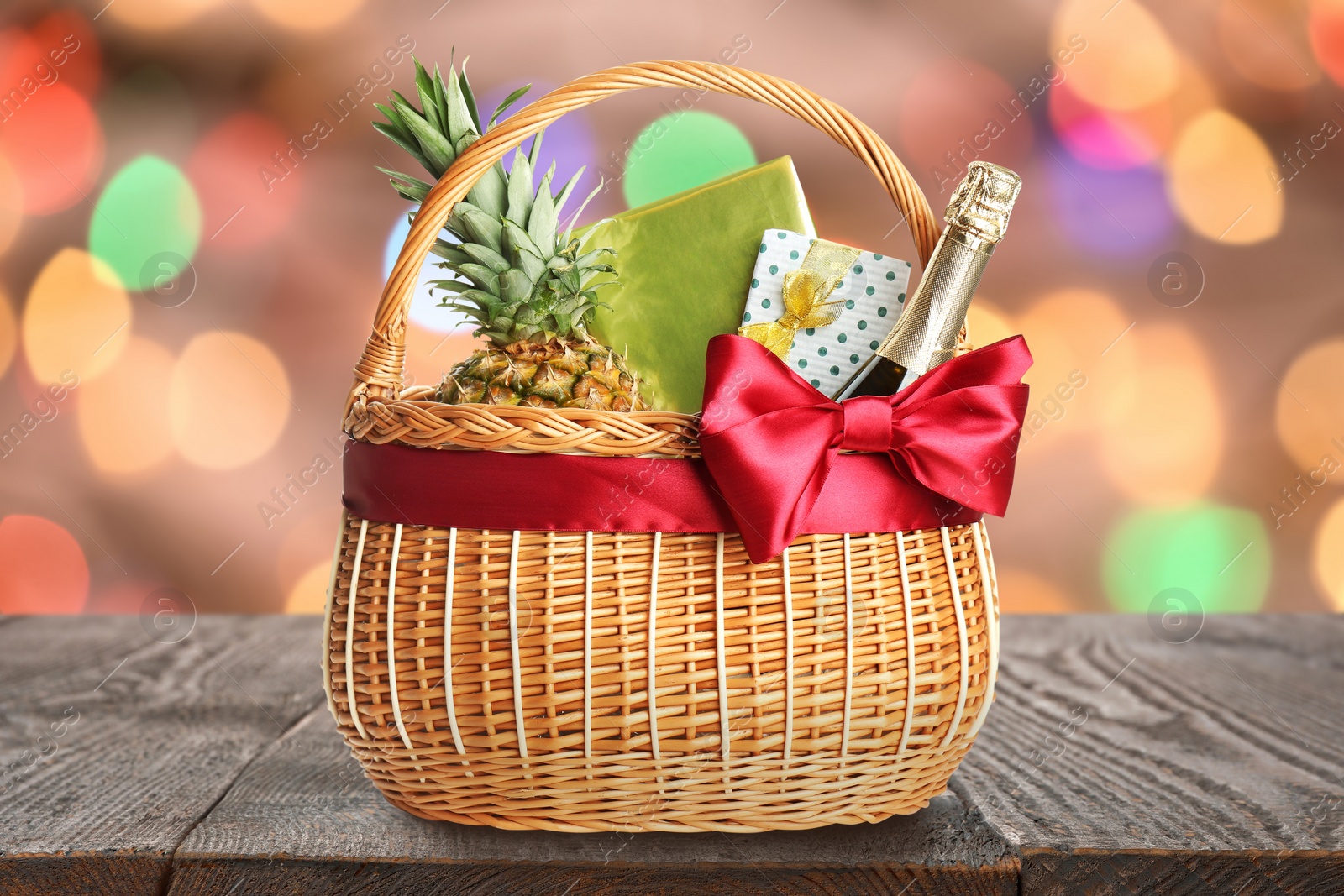 Wicker basket full of gifts on wooden table against blurred festive lights Image of Wicker basket full of gifts on wooden table against blurred festive lights