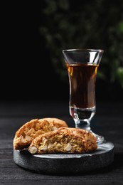 Photo of Tasty cantucci and glass of liqueur on wooden table. Traditional Italian almond biscuits