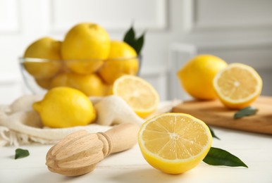 Photo of Wooden citrus reamer and fresh lemons on white table