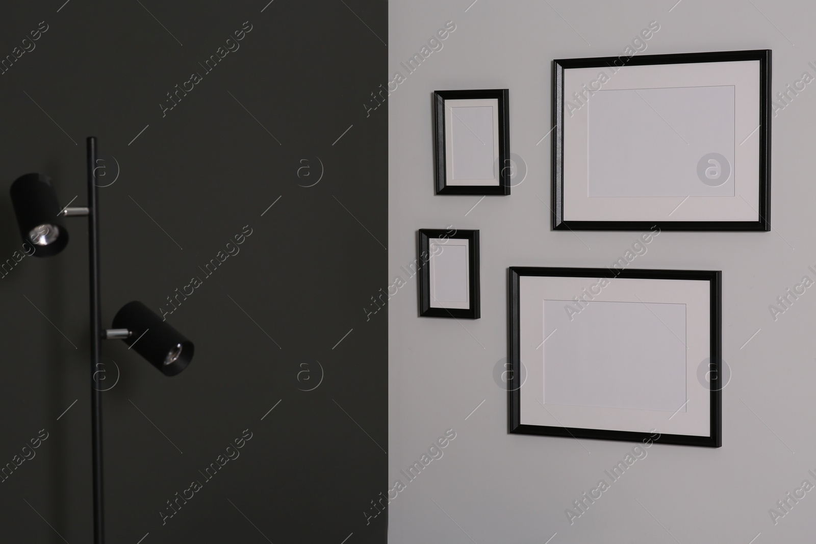 Photo of Empty frames hanging on white wall near lamp indoors