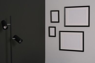 Photo of Empty frames hanging on white wall near lamp indoors