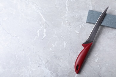 Photo of Boning knife, sharpening stone and space for text on grey background, flat lay