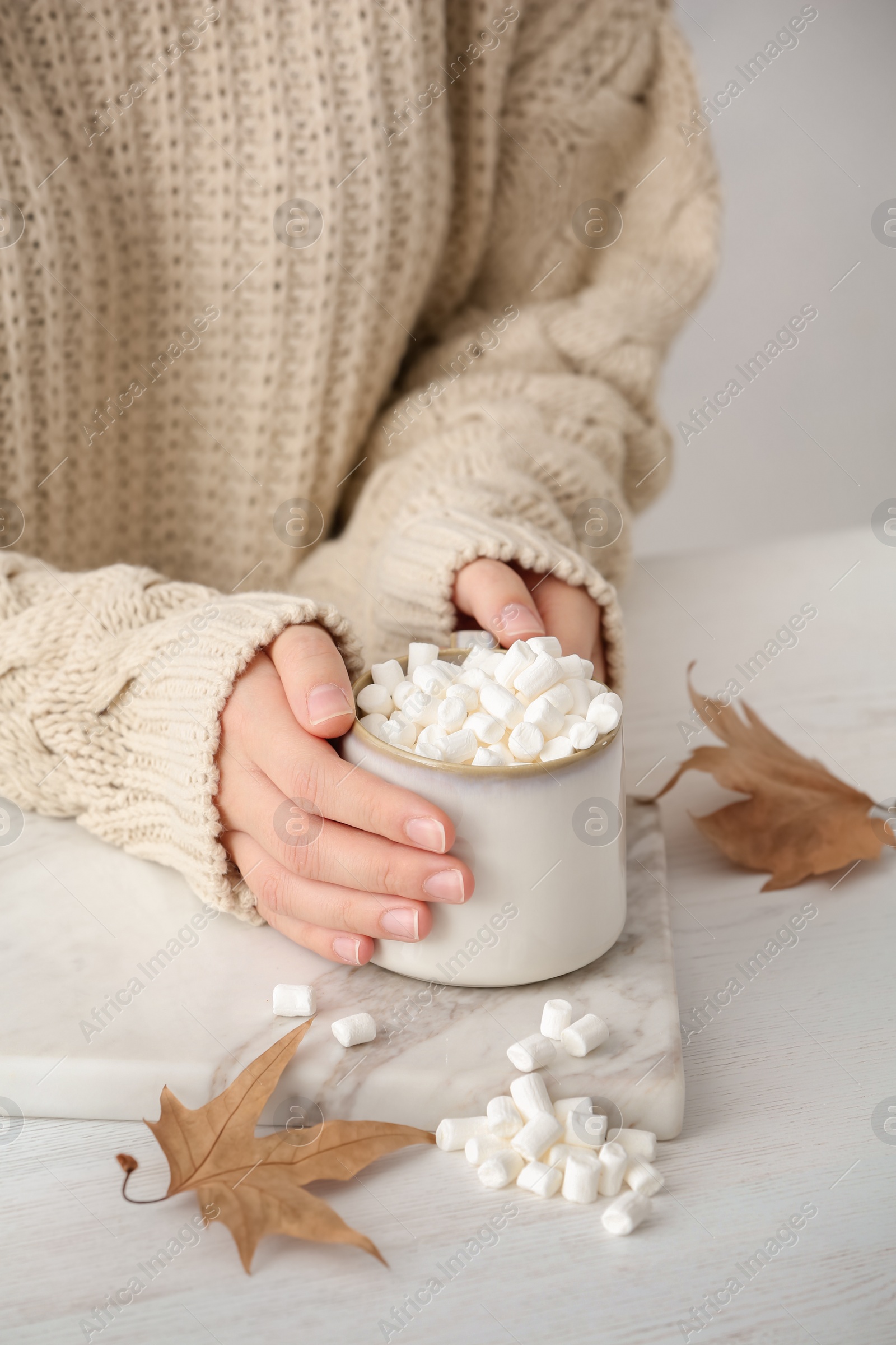 Photo of Woman in autumn sweater holding hot cozy drink at table