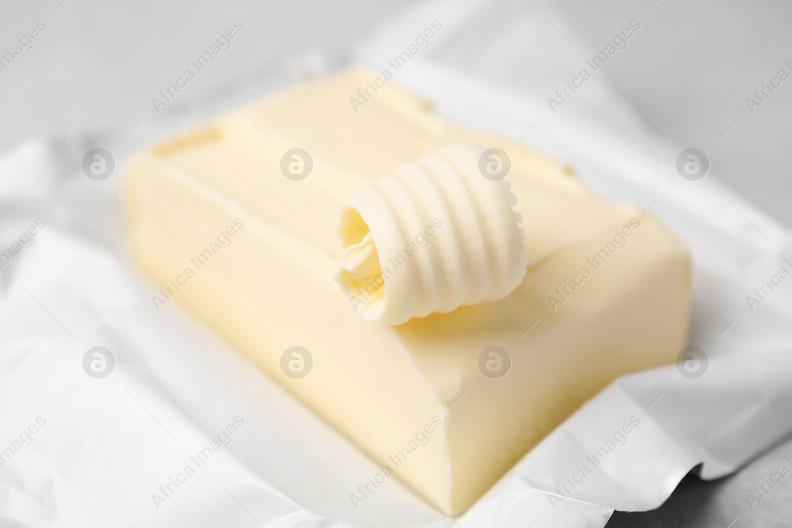 Photo of Tasty butter and curl on light grey table, closeup