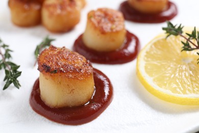 Delicious fried scallops with tomato sauce and lemon on plate, closeup