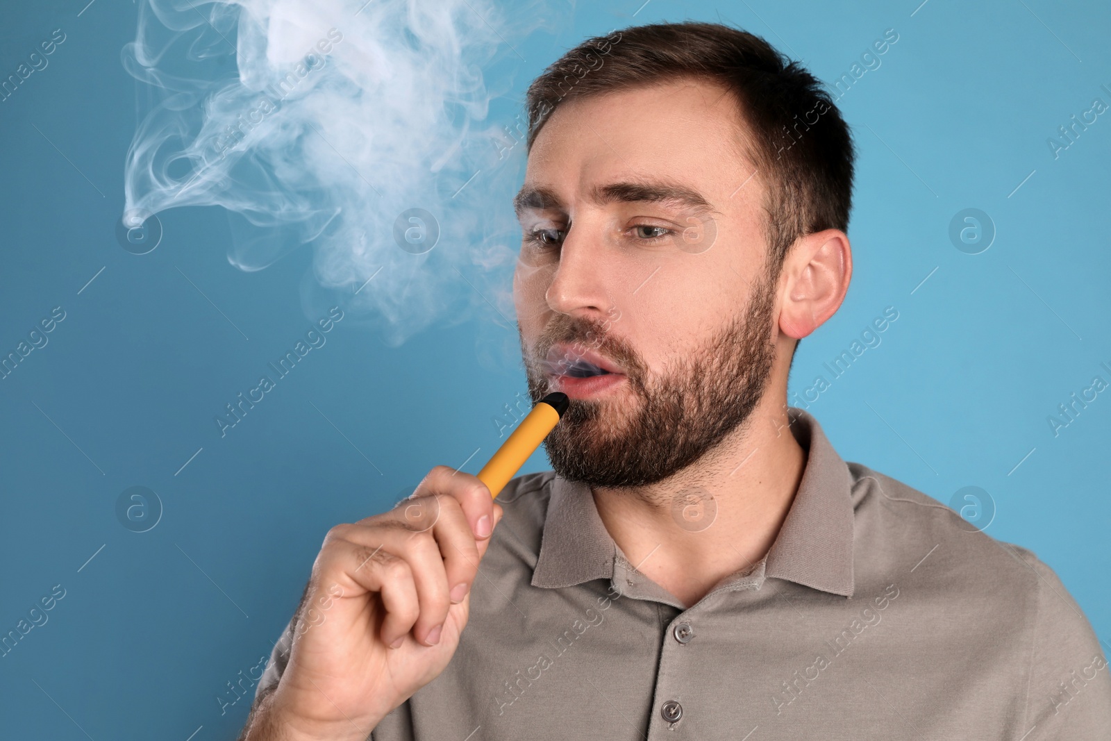 Photo of Man using electronic cigarette on light blue background