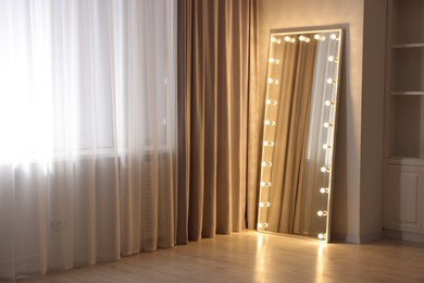 Photo of Modern mirror with light bulbs in makeup room