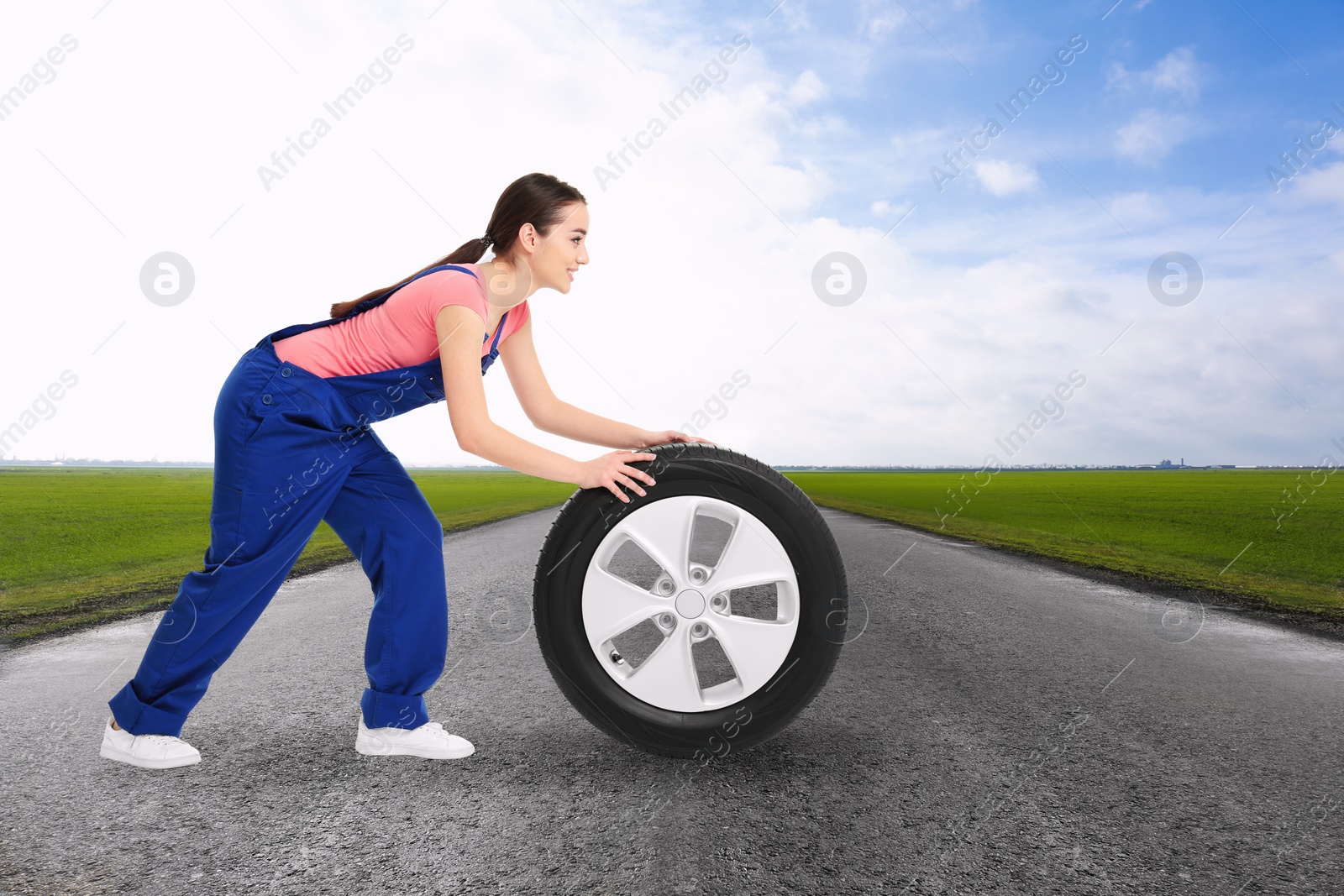 Image of Mechanic with car tire on asphalt highway outdoors