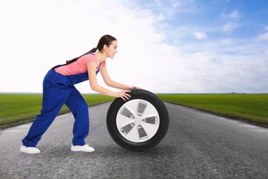 Image of Mechanic with car tire on asphalt highway outdoors