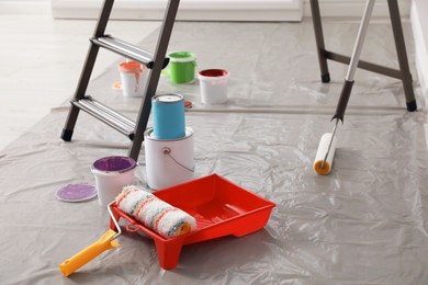 Photo of Different paints and decorator's tools near ladder indoors
