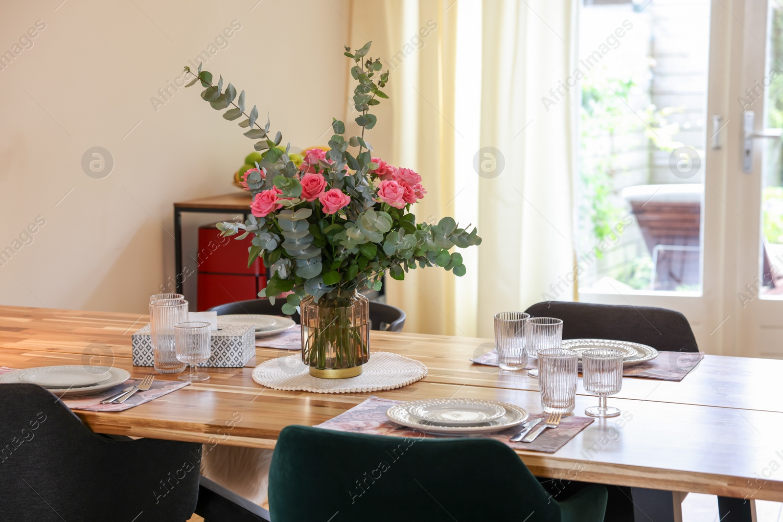 Photo of Beautiful table setting with bouquet indoors. Roses and eucalyptus branches in vase