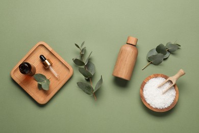Photo of Aromatherapy products. Bottles of essential oil, sea salt and eucalyptus leaves on olive background, flat lay