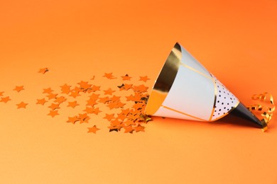 Party hat and confetti on orange background