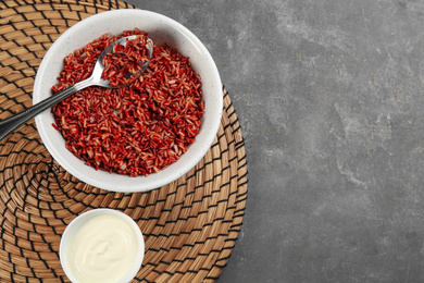 Photo of Tasty brown rice with vegetables served on grey table, flat lay. Space for text