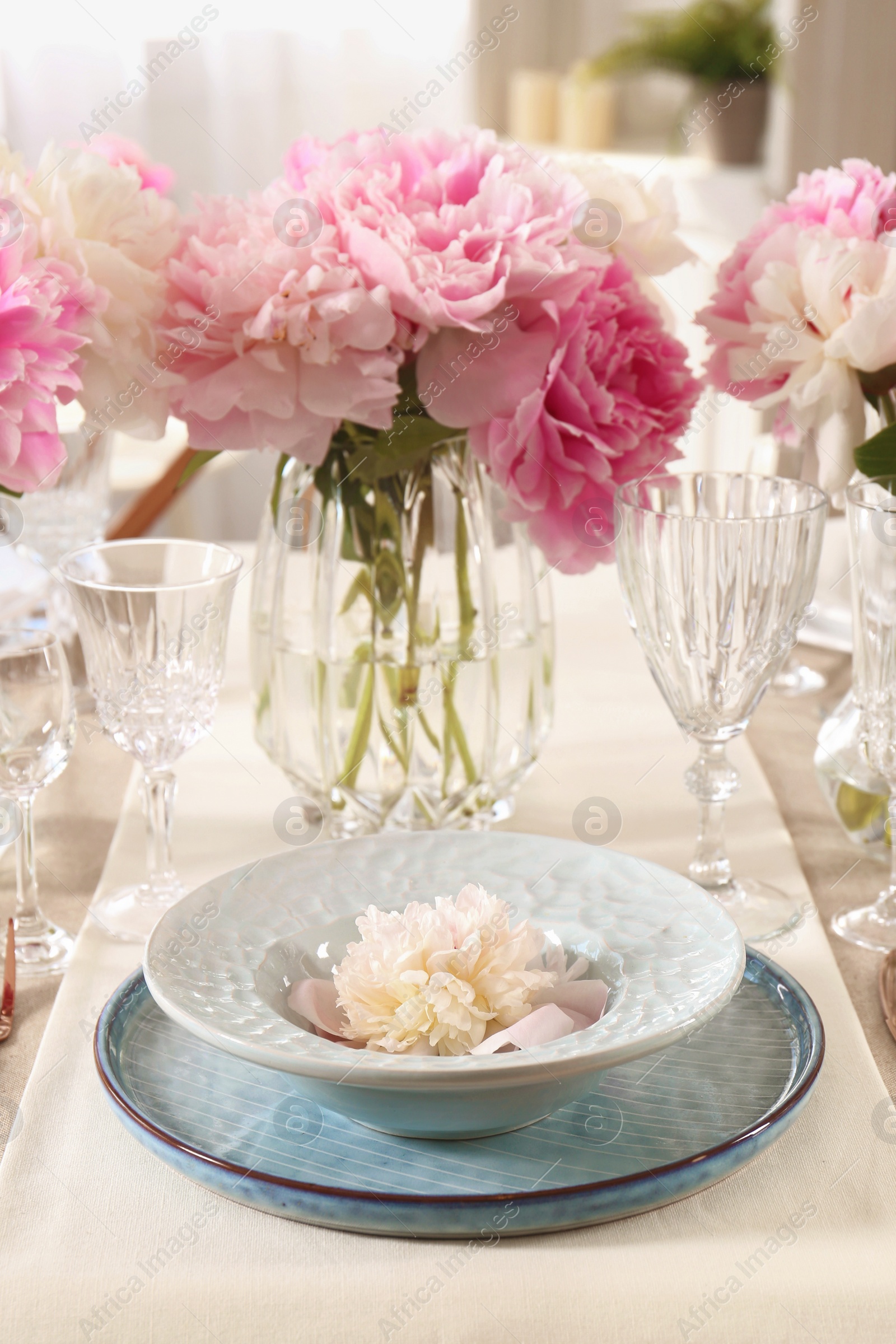 Photo of Stylish table setting with beautiful peonies and golden cutlery indoors