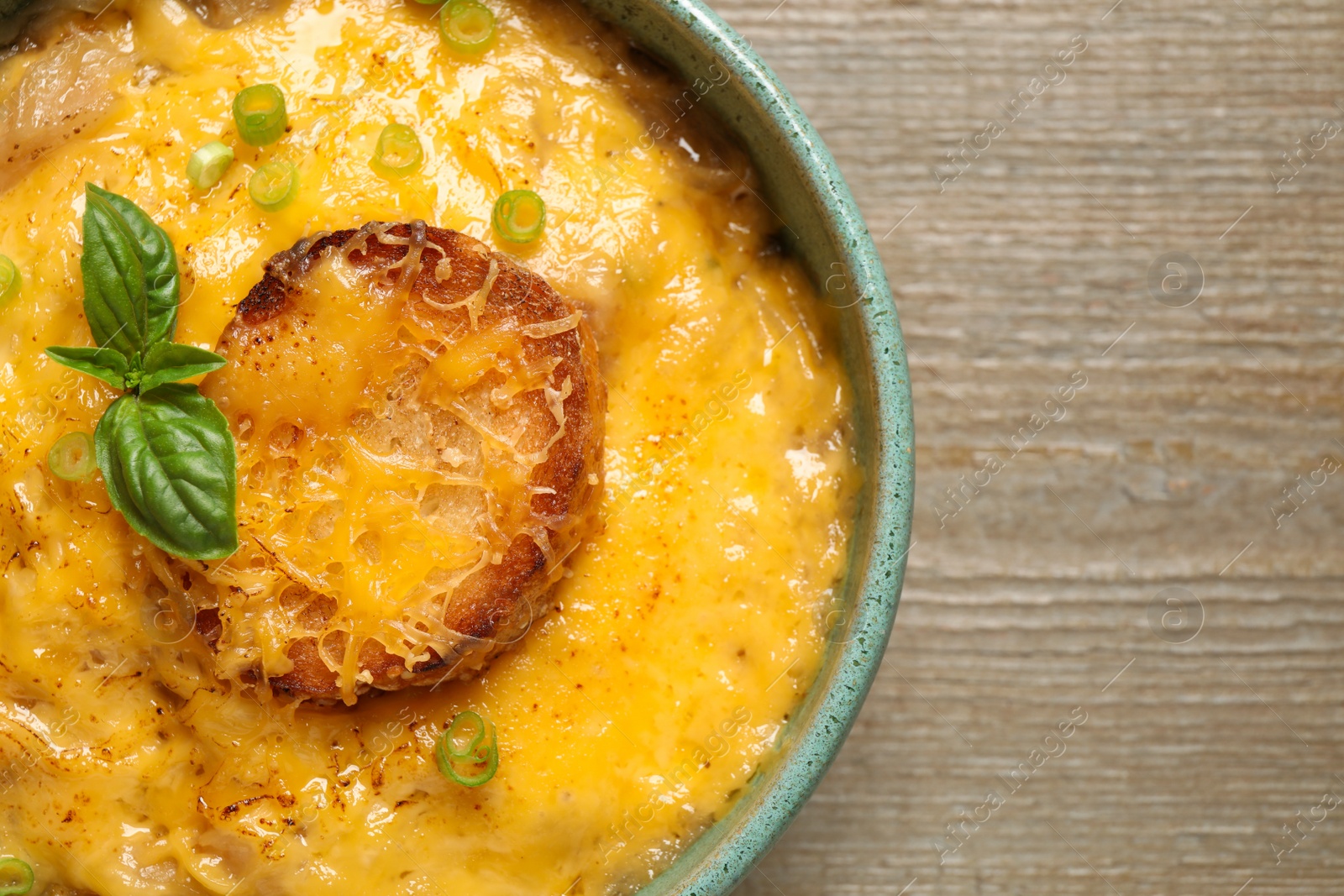 Photo of Tasty homemade French onion soup on wooden table, top view