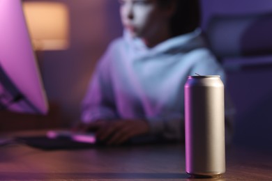 Photo of Girl playing computer game at home, focus on can with energy drink