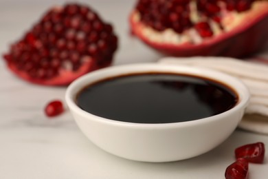 Photo of Bowl of pomegranate sauce on white marble table, closeup