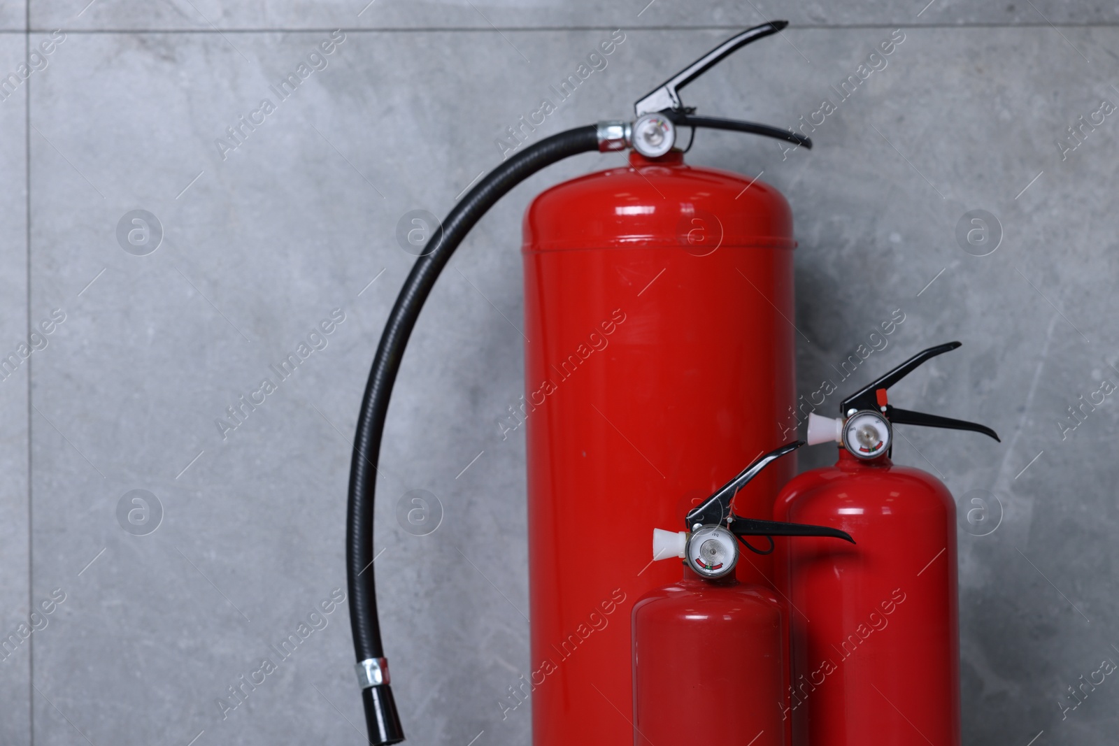 Photo of Fire extinguishers near grey wall, space for text